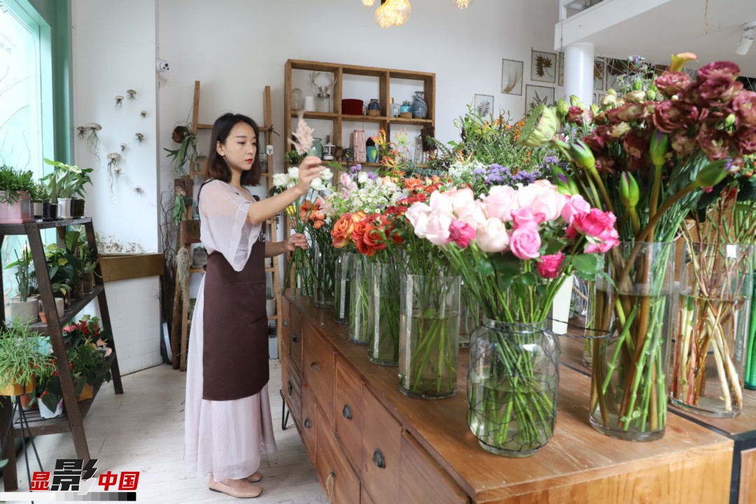 王黎媛是一名河南姑娘，在昆明念完大學后，就再也舍不下春城的藍天陽光、青山碧水，更舍不下這里的四時繁花，于是就干脆留了下來，成了一名媒體人。2017年的時候又毅然辭去工作，創(chuàng)業(yè)開起了花店，成了都市里的一名“花房姑娘”。圖為王黎媛在自己的花店中整理鮮花。新華網(wǎng) 周亞平/攝 念新洪/文